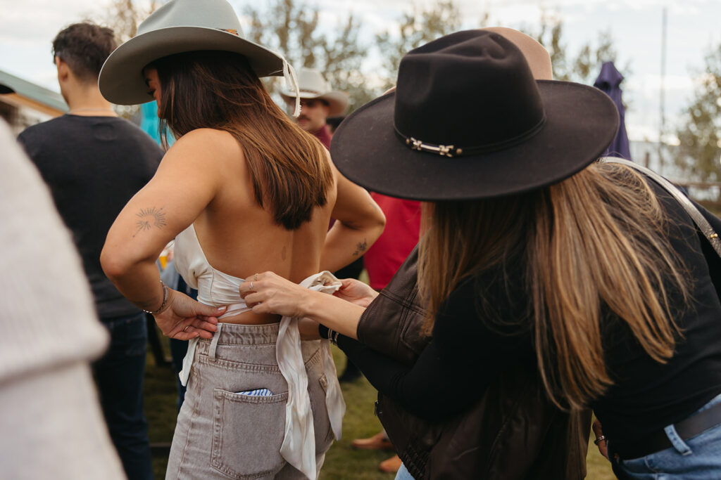 Friend helps bride-to-be fix her top. 