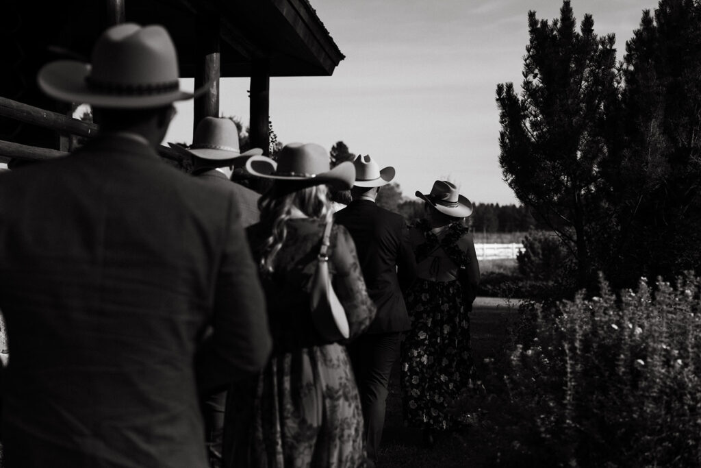 Wedding guests in cowboy hats walk towards the ceremony for Yellowstone wedding