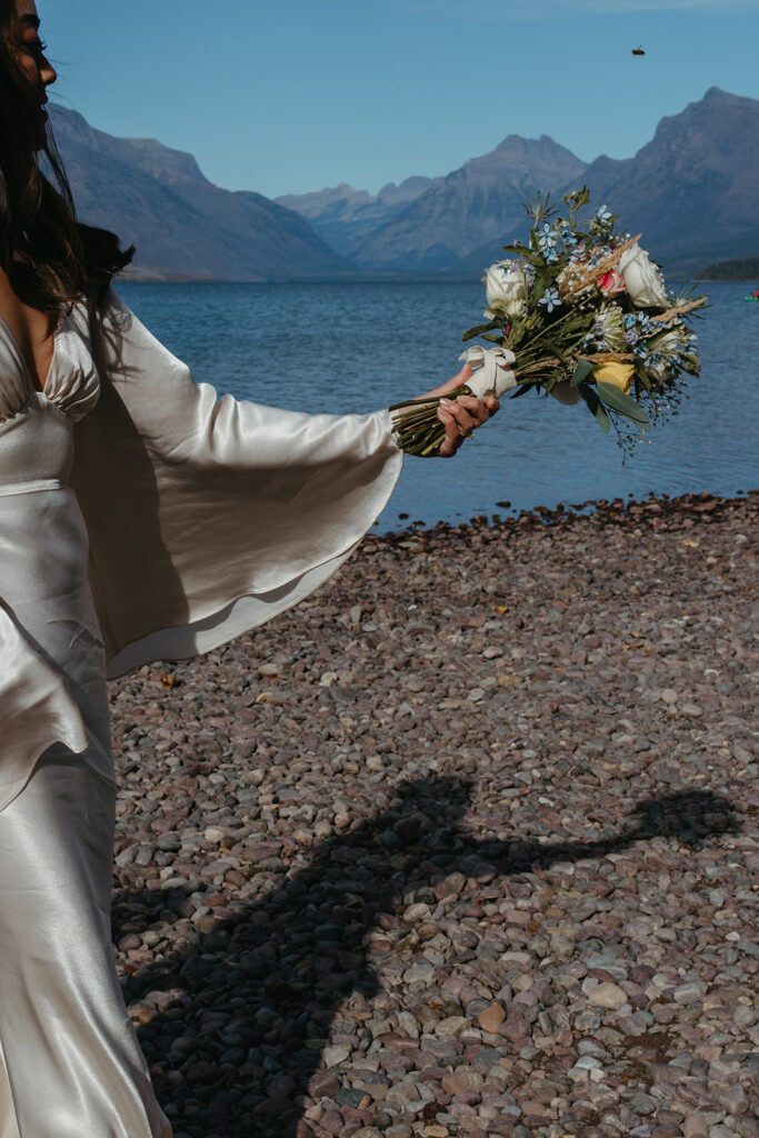 Bride prepares to toss her bouquet in the air as Montana mountains show off in the distance. 