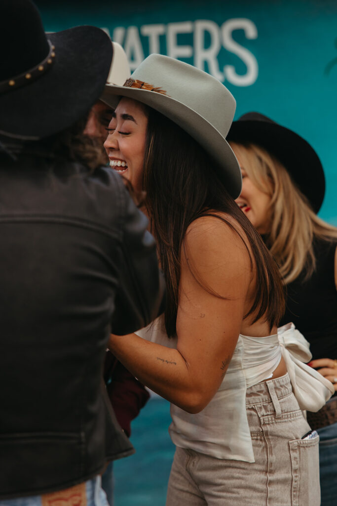 Bride laughs at something a friend showed her on her phone. 