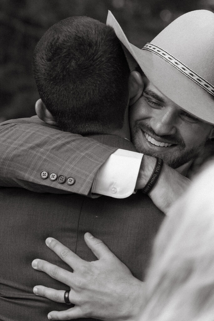 Wedding guest hugging groom to congratulate him.