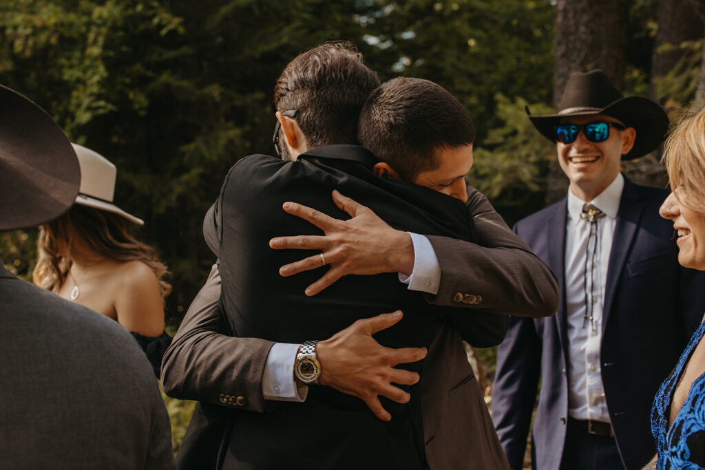 Groom embraces wedding guest. 