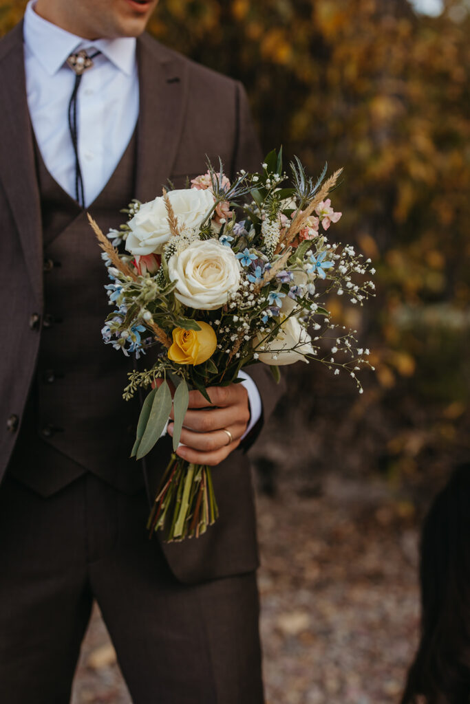 Groom holds bride's bouquet. 