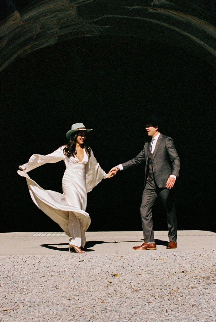 Bride and groom run through Montana highway. 