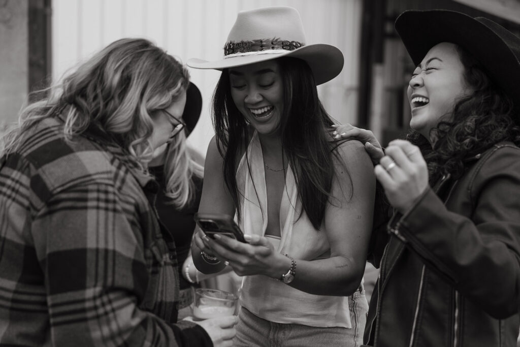 Bride and friends giggle over something on the bride's phone. 