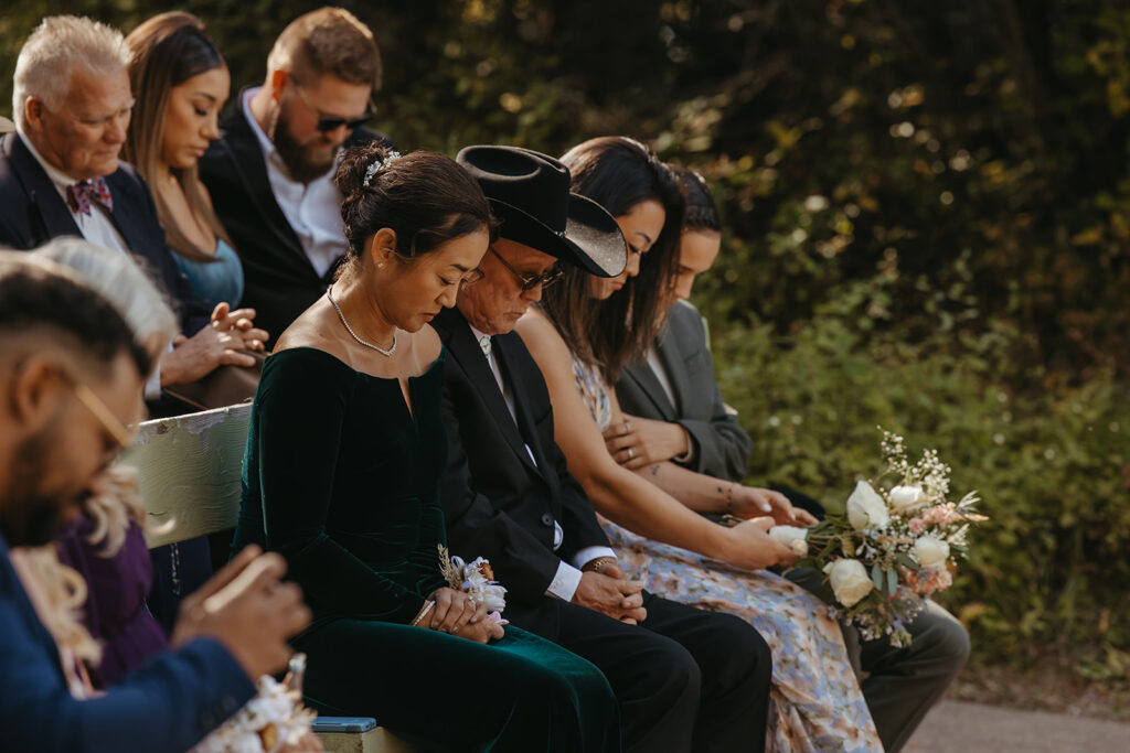 Bride's family bows their heads in prayer in Yellowstone wedding.