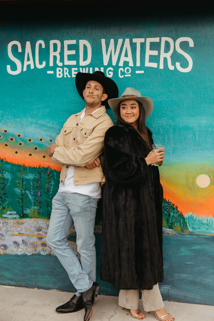 Bride and groom pose in front of Sacred Waters Brewing Co. sign in Montana.