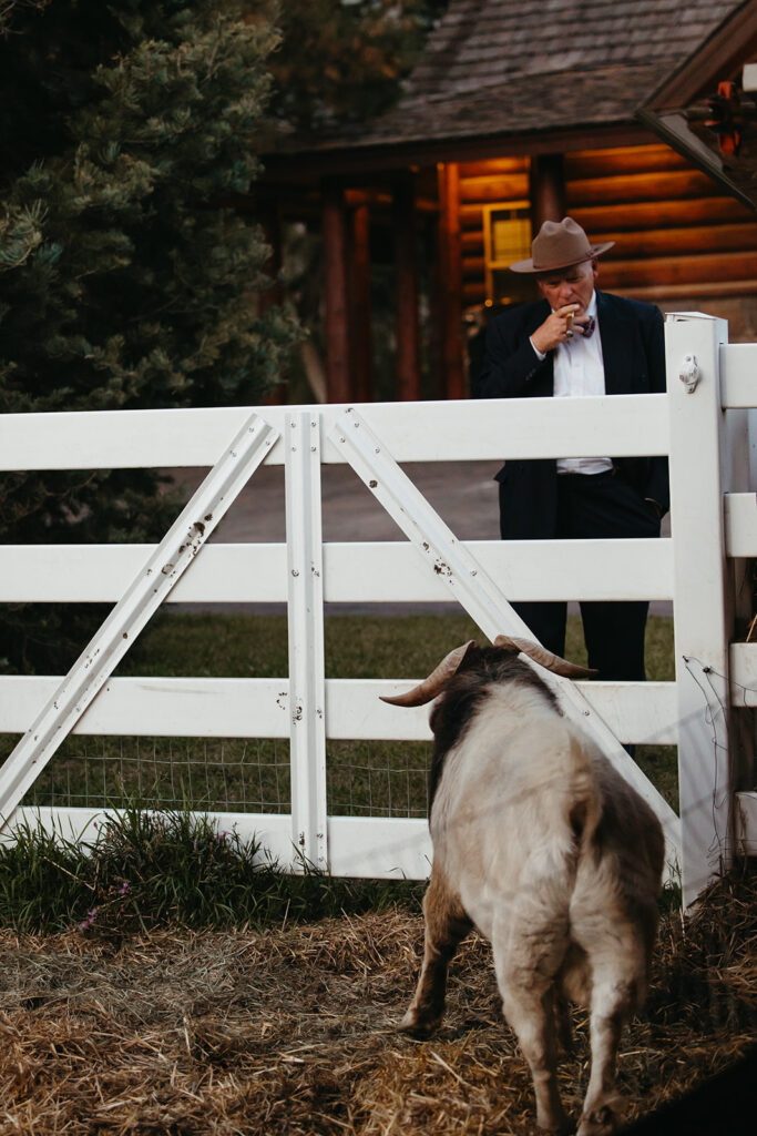 Wedding guest in cowboy hat smokes a cigar while looking at a coat on the property of Yellowstone wedding