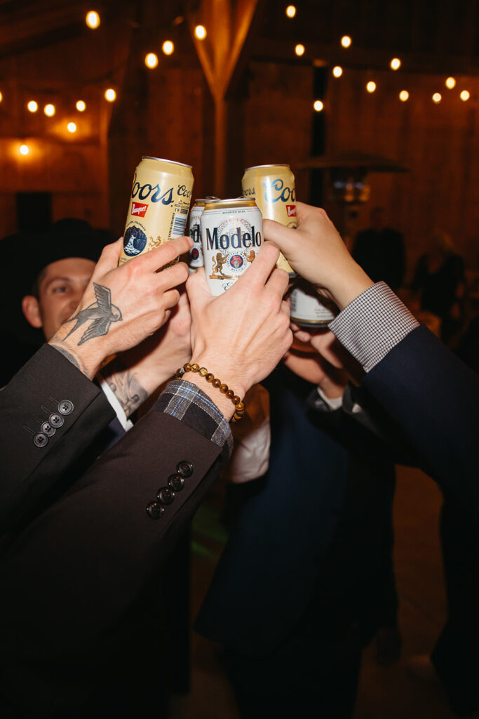 Groom and friends raise their beer cans in a toast during Montana wedding