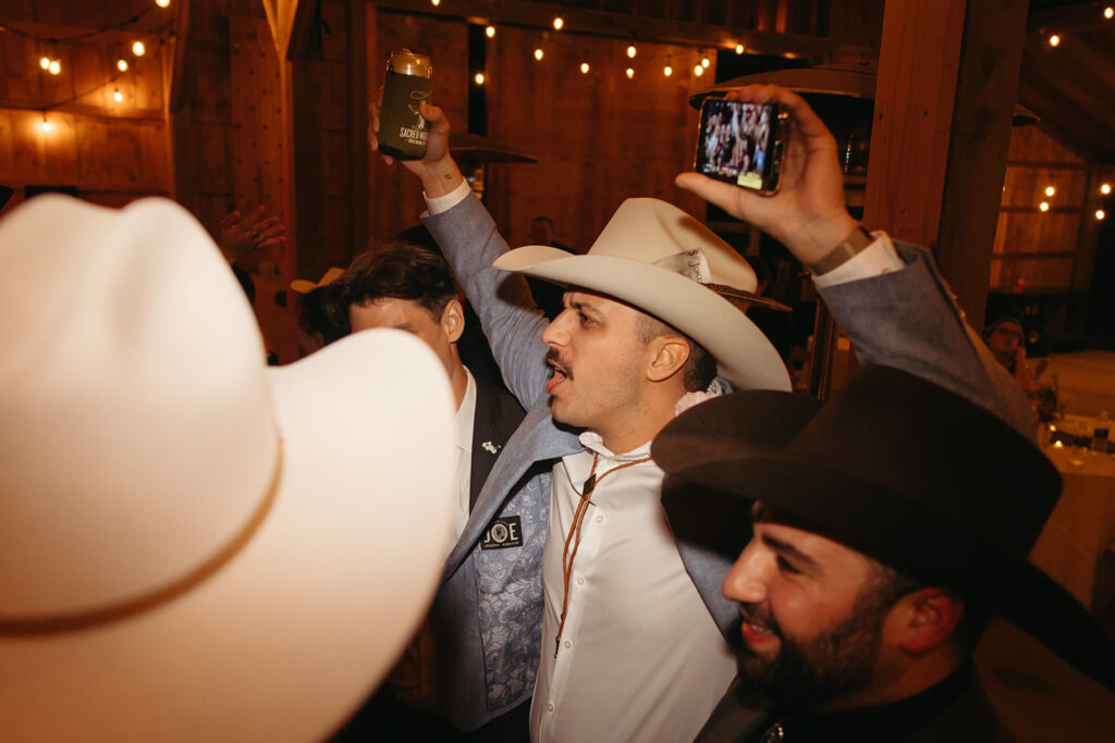 Wedding guests raise their hands in the air on the dance floor