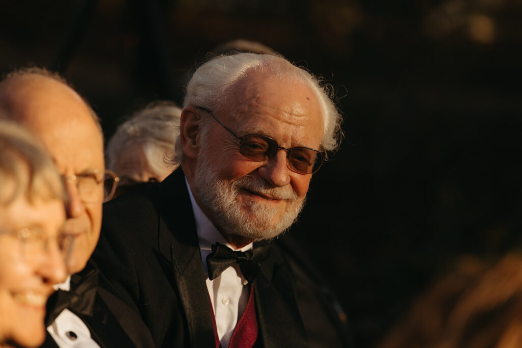 Elderly man smiles during autumnal wedding ceremony