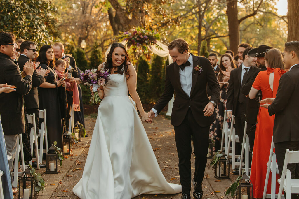 Bride and groom grin from ear to ear as they come back down the aisle at black tie wedding in Nashville