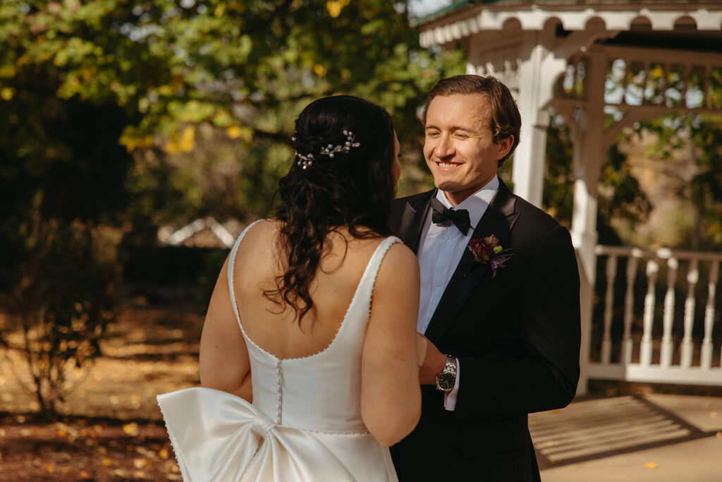 Groom smiles at his bride during their first look at black tie wedding in Nashville