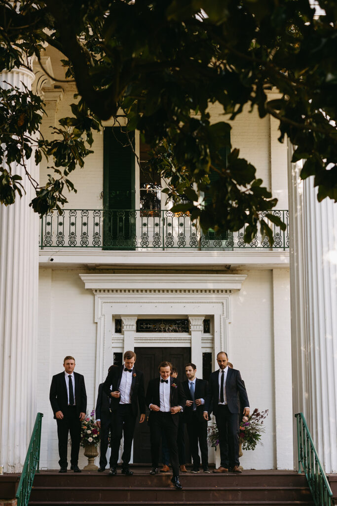 Groom and groomsmen walk down stairwell of Riverwood Mansion in Nashville