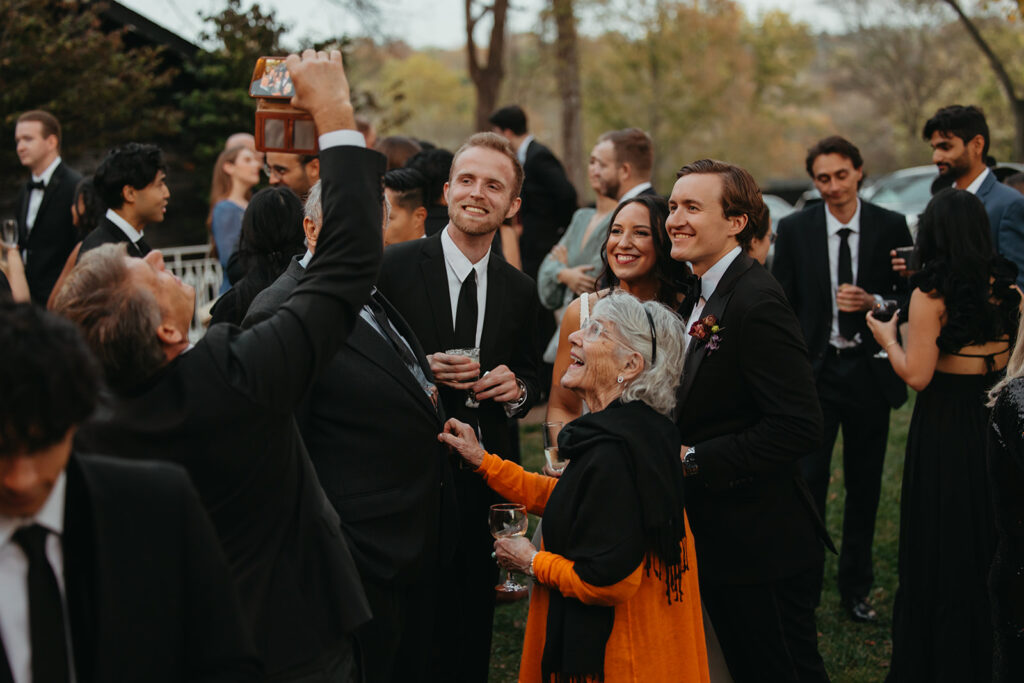 Wedding guests takes iPhone photo of the bride and groom during cocktail hour of their black tie wedding in Nashville