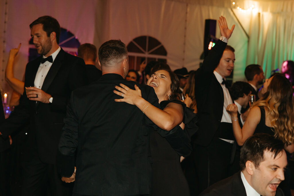 Wedding guest throws her head back in laughter during black tie wedding reception in Nashville