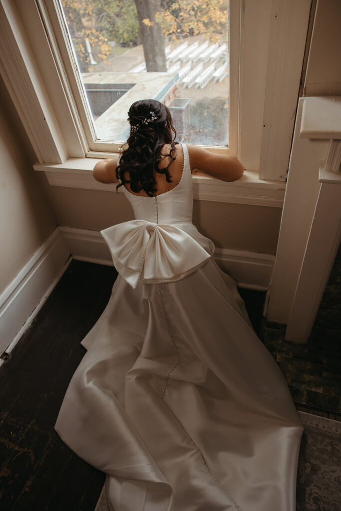 Bride peeks out window from her knees in anticipation of her first look with her husband to be