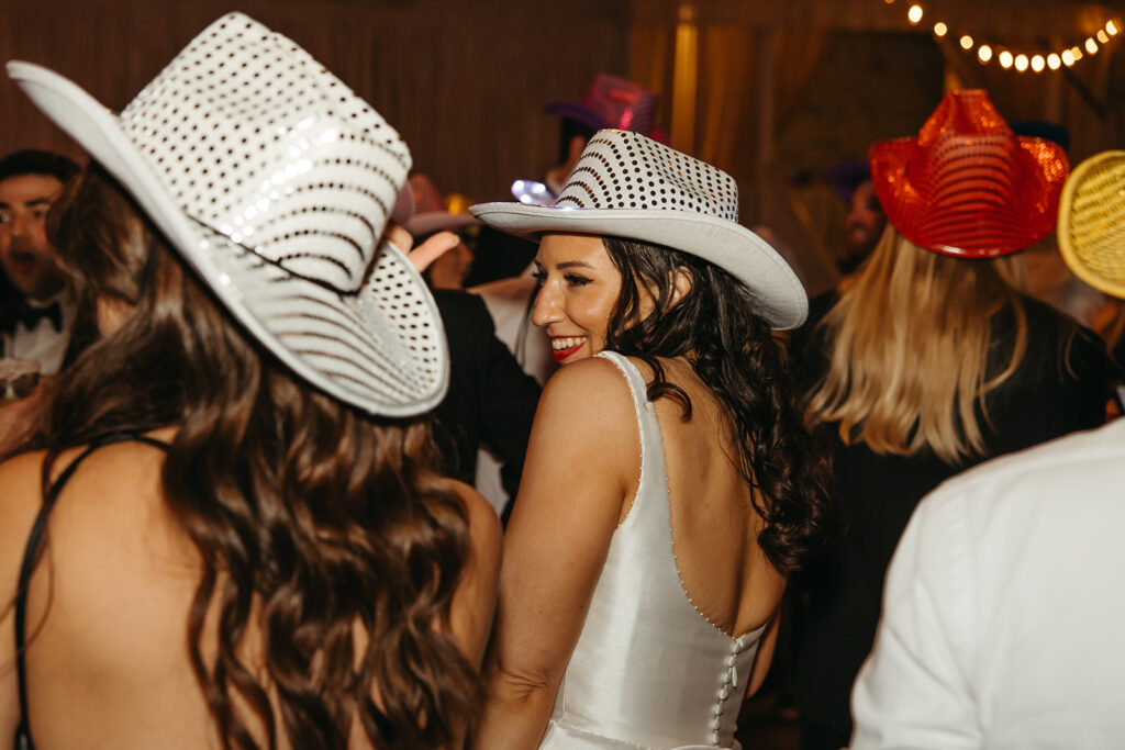 Bride wearing white cowboy hat enjoys her black tie wedding in Nashville reception