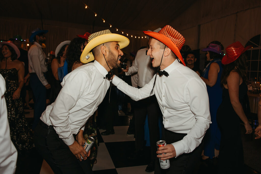 Wedding guests wearing neon cowboy hats serenade each other during black tie wedding reception in Nashville