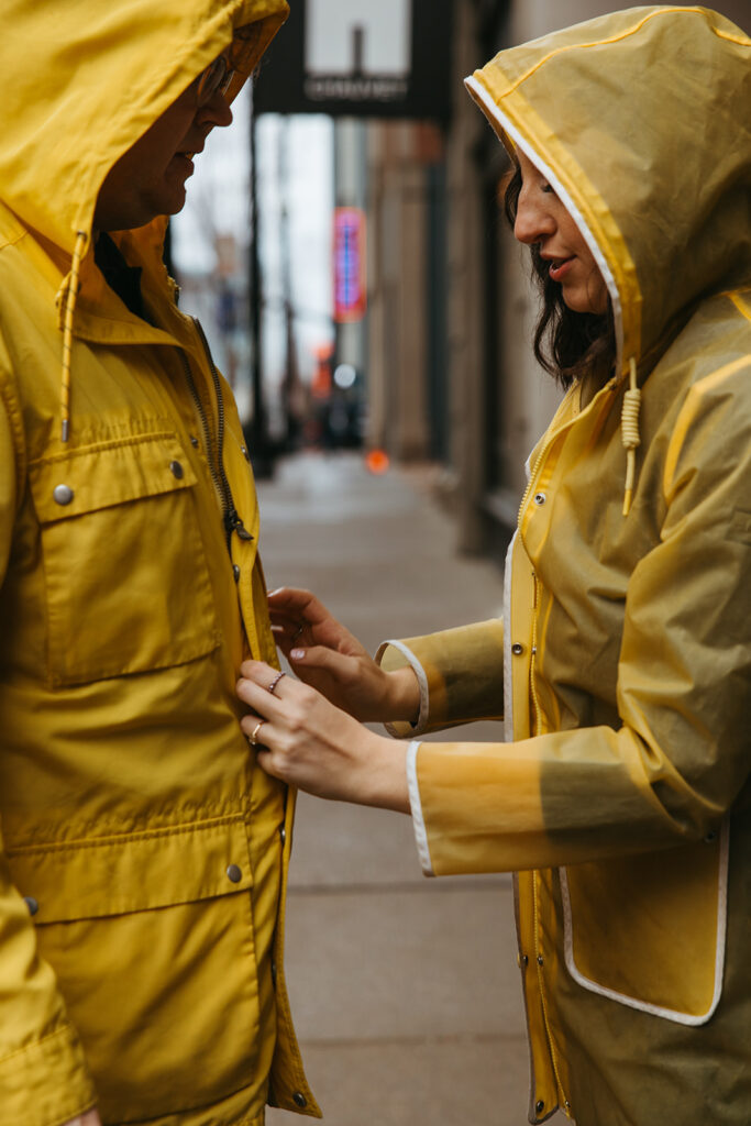 Woman fixes her fiance's yellow rain jacket as the rain begins to fall