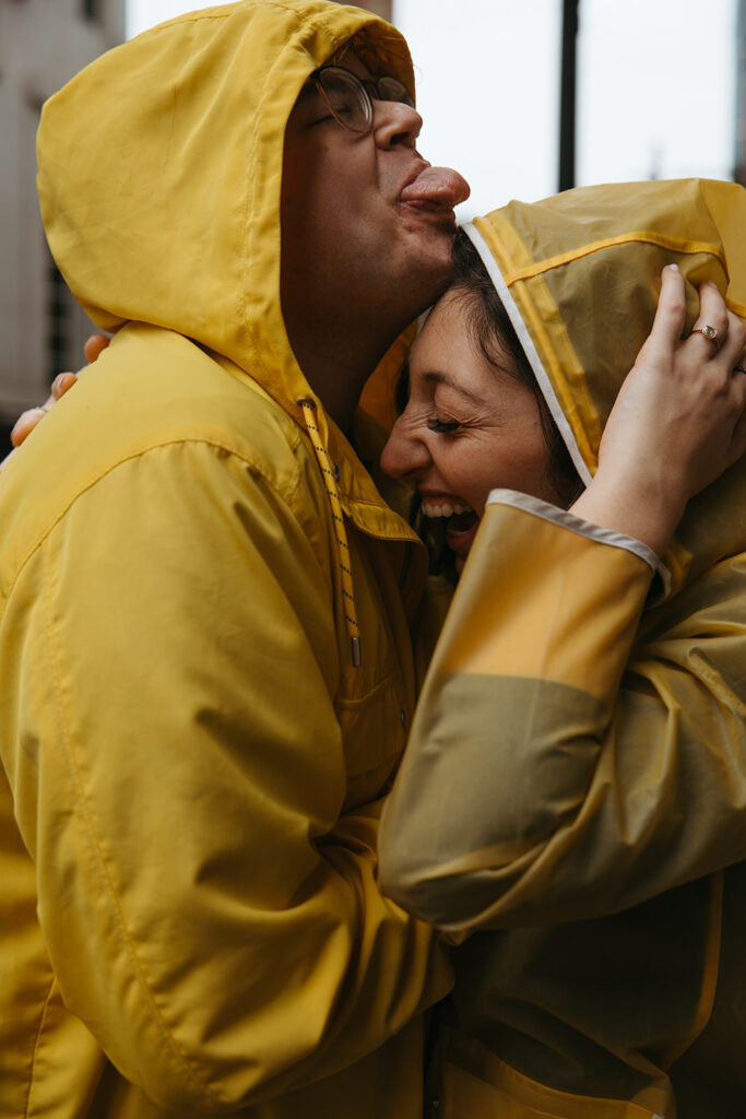 Couple in yellow rain jackets plays in the rainy streets of Nashville.