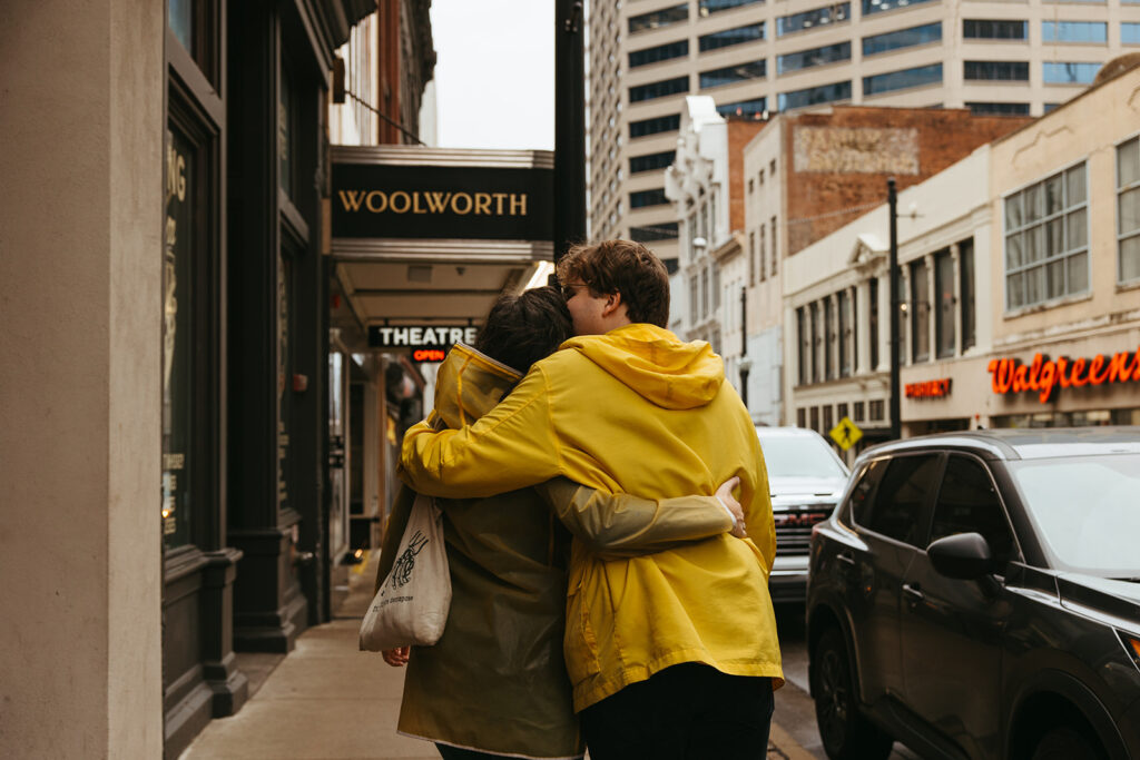 Engaged couple walks arm in arm through the streets of rainy downtown Nashville