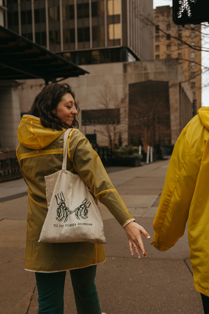 Woman reaches for her fiance's hand as they walk in the pouring rain