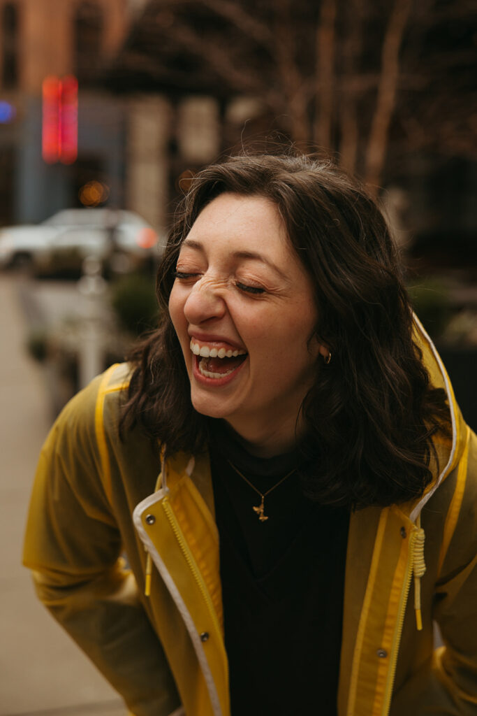 Woman wearing yellow rain jacket doubles over in laughter