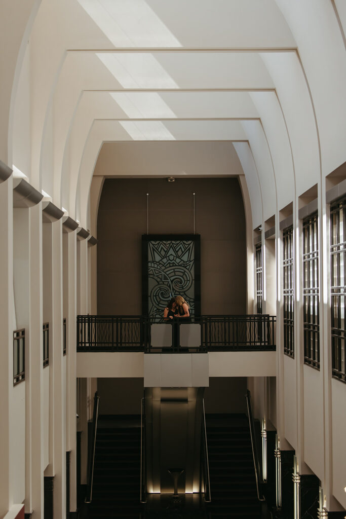 Engaged couple stands at balcony overlooking lobby of Frist Art Museum in downtown Nashville