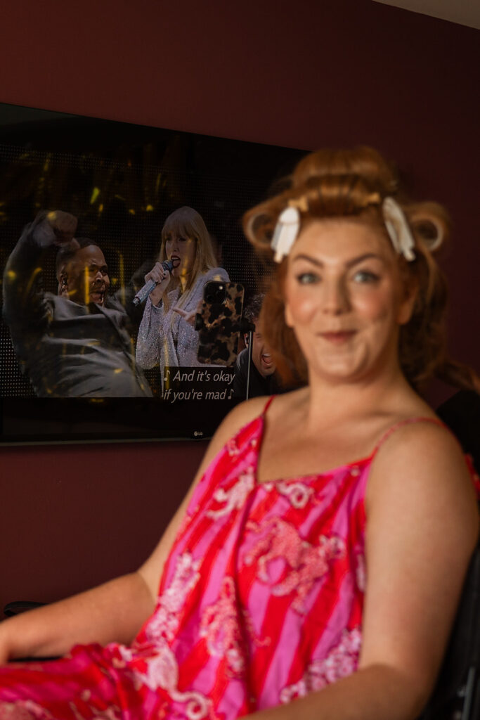 Bride sits with curlers in her hair while Taylor Swift Eras Tour plays in the background