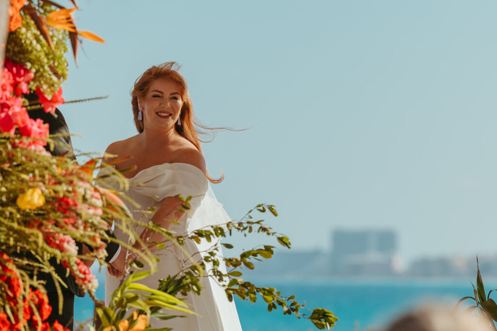 Bride looks out at sea of wedding guests who travelled in for her destination wedding in Mexico with utter admiration