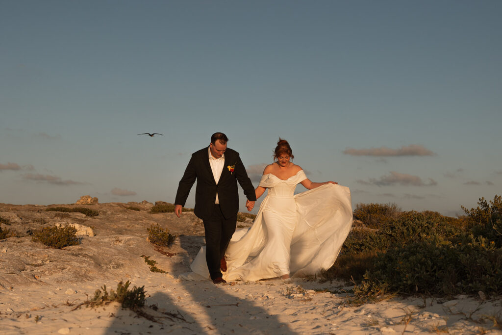 Newlyweds walk in the sand on shoreline of Cancun, Mexico destination wedding