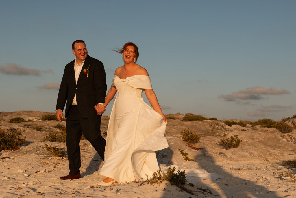 Bride and groom walk hand in hand down the sandy shoreline of Cancun, Mexico