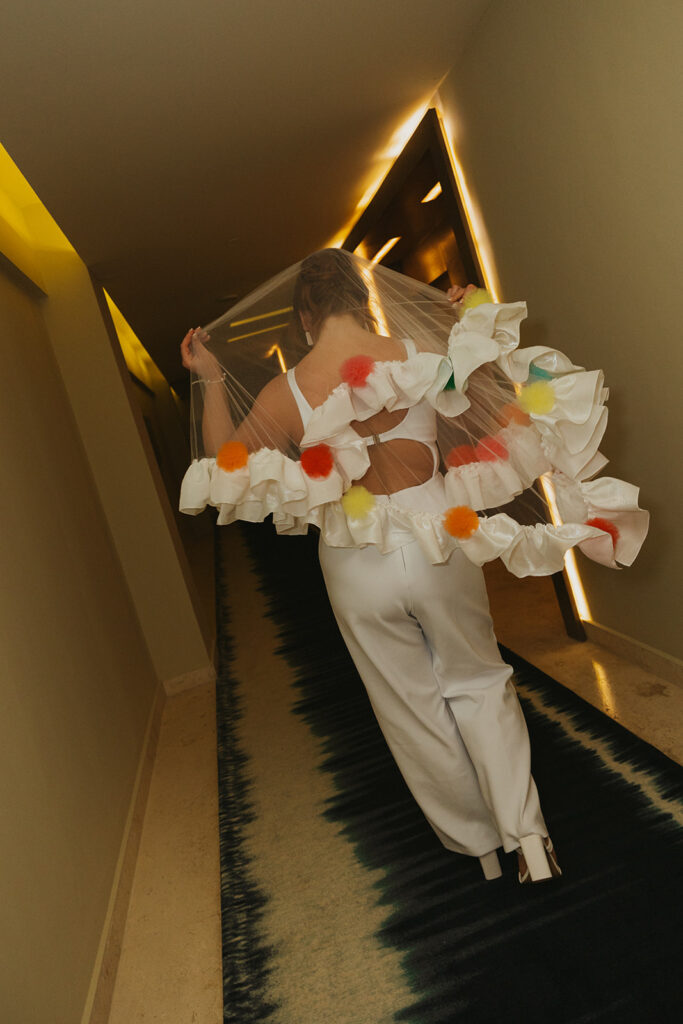 Bride wearing custom made, colorful veil walks down the hall of the Hyatt Ziva Cancun