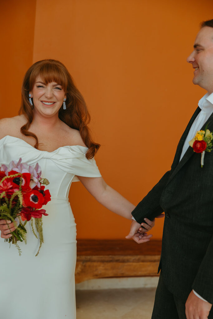 Groom looks at bride while she grins at the camera