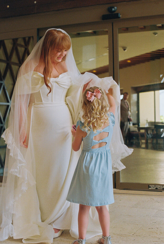 Flower girl looks at bride's veil
