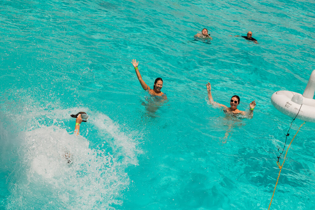Wedding guests jump into the teal water of Cancun