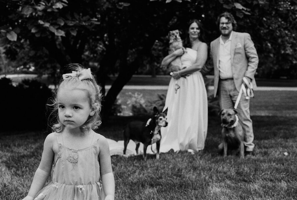 Little girl standing in front of a portrait with the bride, groom, and their dogs