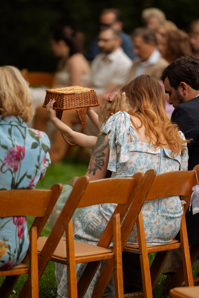 Flower girl turning a wicker basket upside down during the backyard wedding ceremony