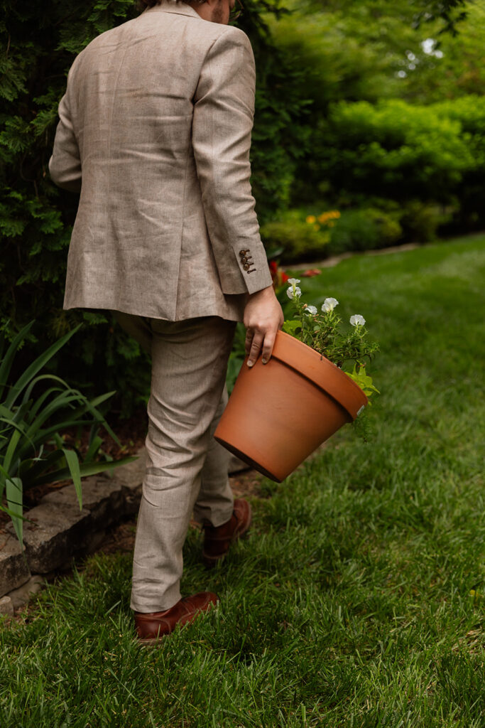 Groom carrying a flower pot with buried whiskey—a Southern tradition at this Tennessee outdoor wedding