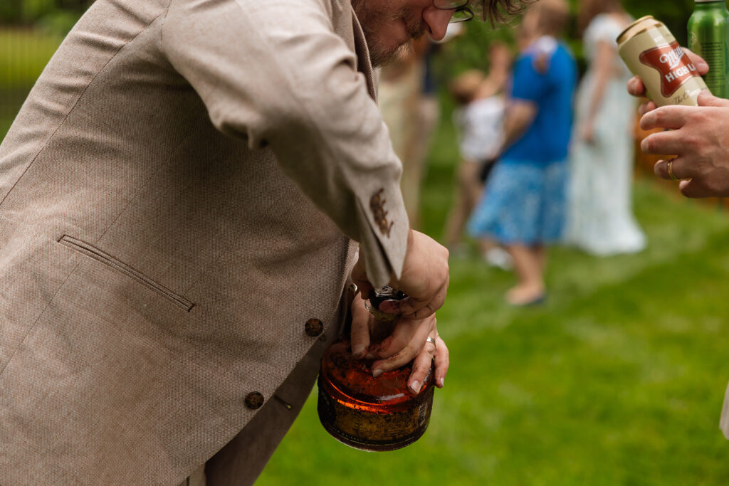 Groom holding the mud-covered whiskey bottle after digging it up