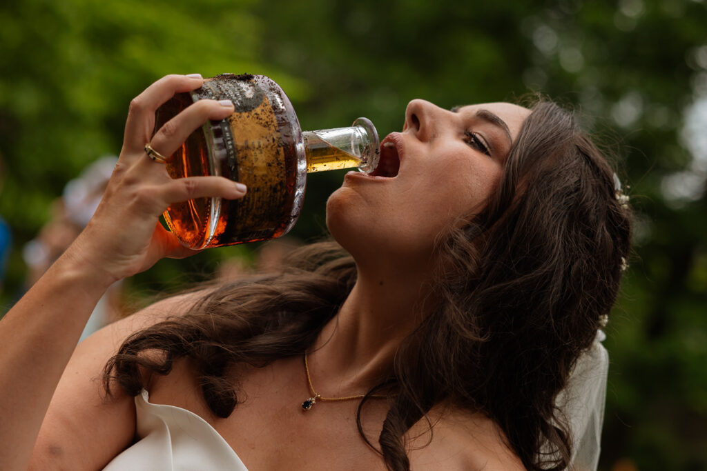 Bride taking a swig of whiskey straight from the bottle during the celebration