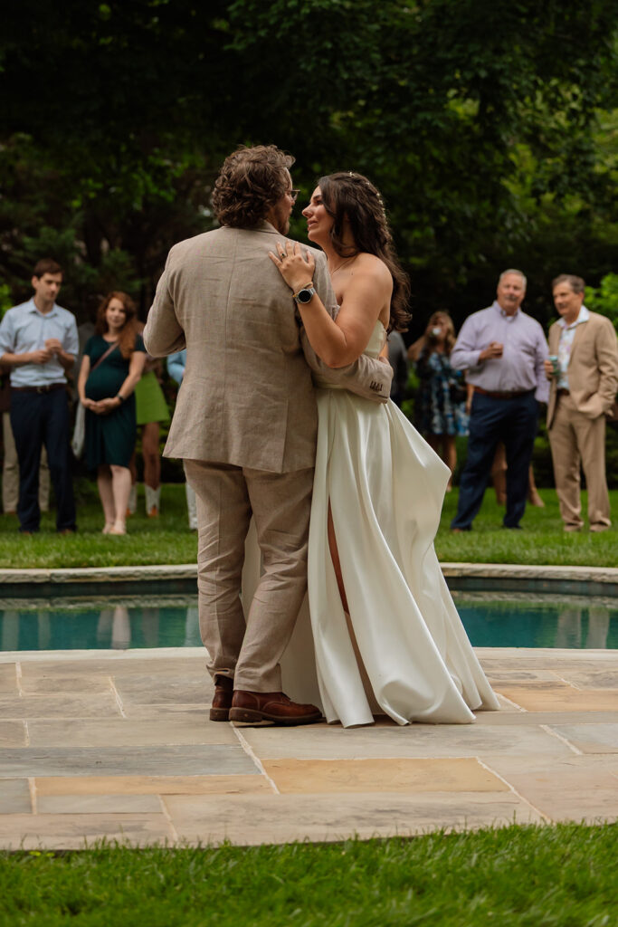 Bride and groom sharing their first dance by the pool during the backyard wedding