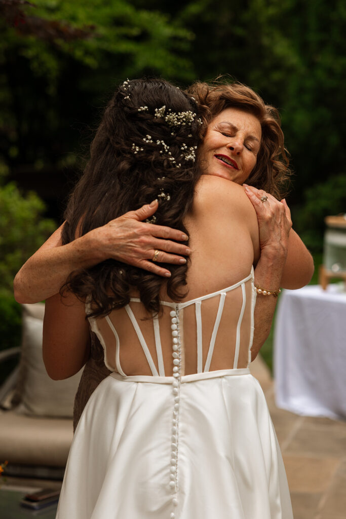 Bride hugging a guest in her corset-back gown during the backyard wedding celebration