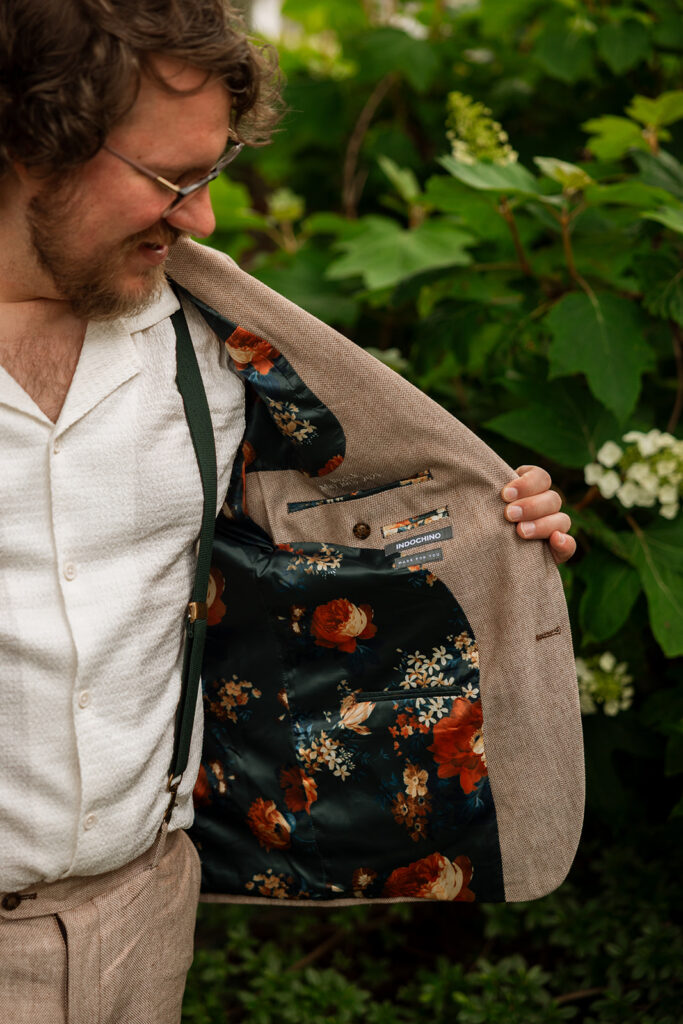 Groom showing the floral lining of his suit jacket with a grin