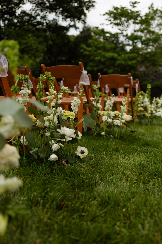 Wildflower-lined aisle and wooden chairs set for the backyard wedding ceremony