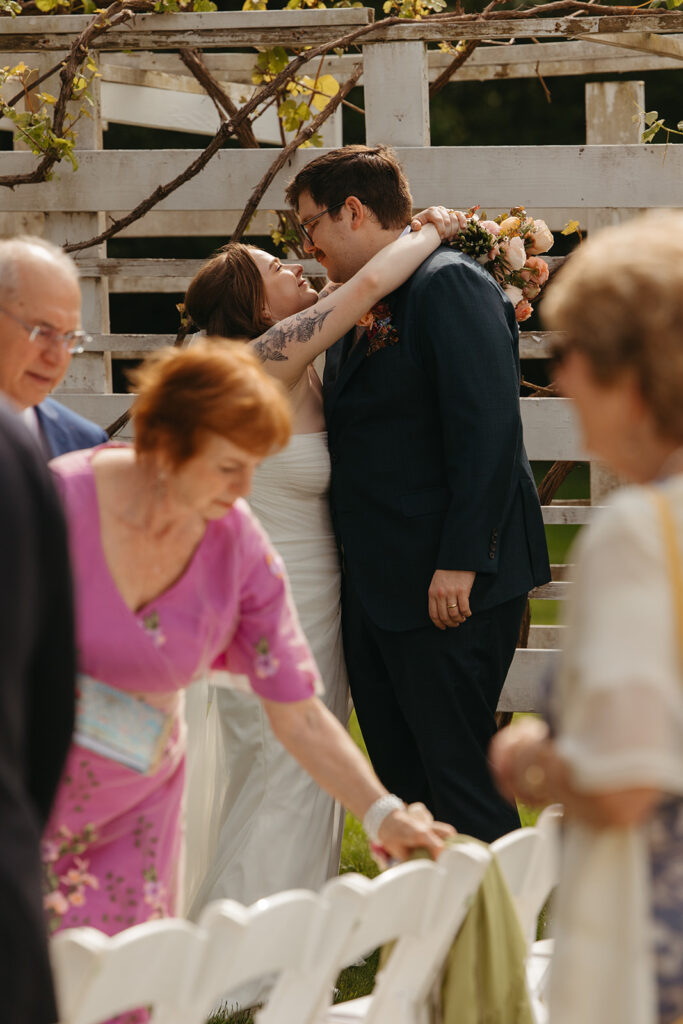 Couple greeting guests with hugs during cocktail hour, candid celebration moment.
