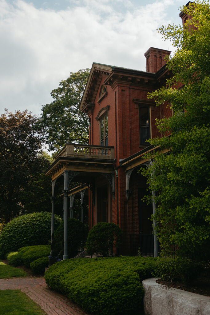Exterior of Commander’s Mansion with greenery, historic red brick glowing in late light.