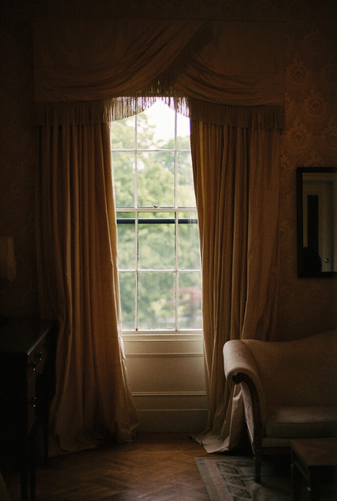 Golden draped curtains framing soft natural light in a historic room at Commander’s Mansion.