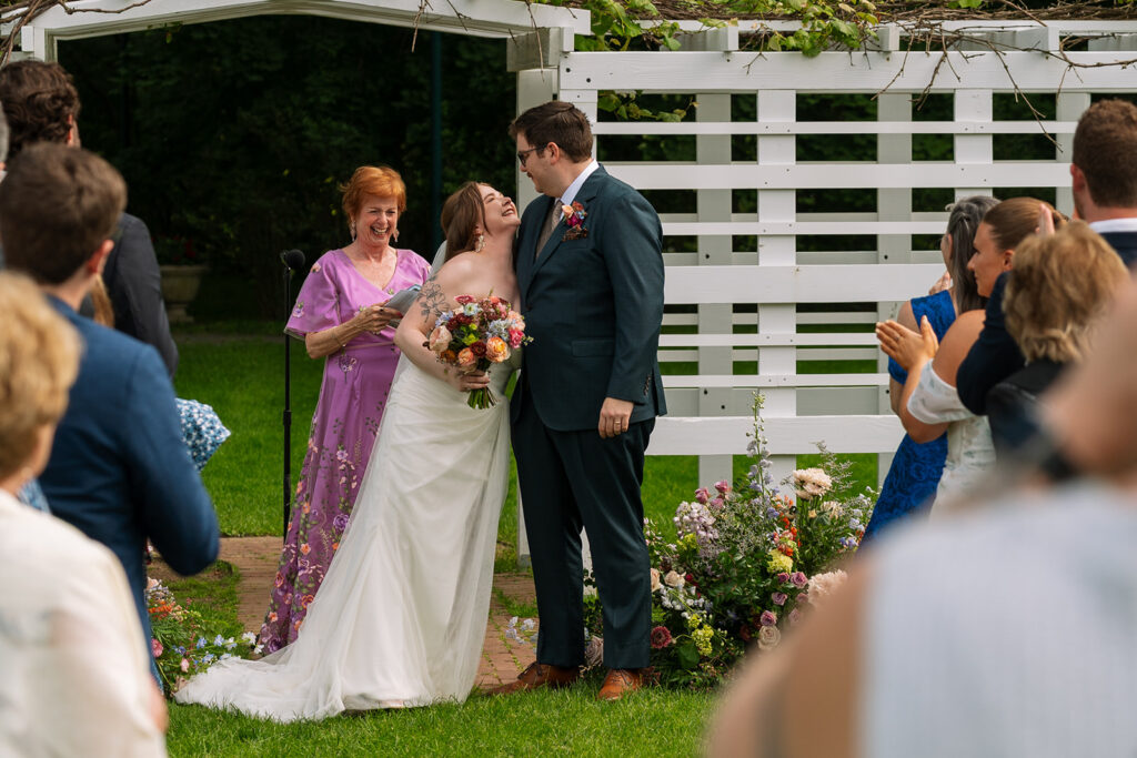 Couple walking down the aisle hand in hand, guests applauding their exit.